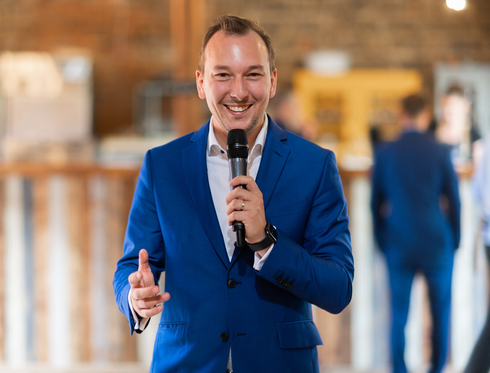 Martin Cihlář moderuje s mikrofonem v ruce ve svatebním sále